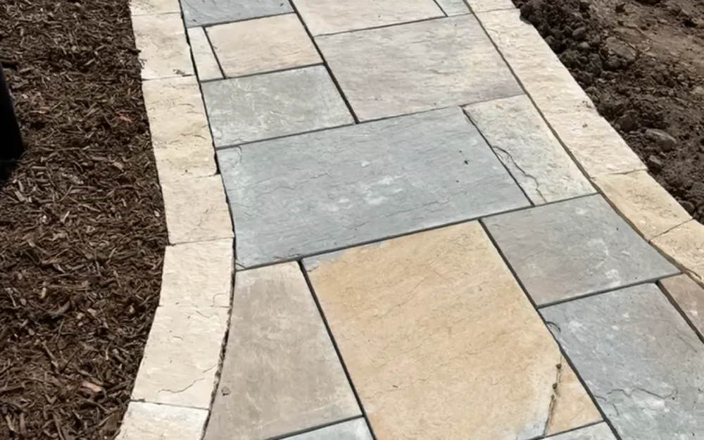 Stone walkway with a contrasting border between fresh planting beds by Larkin Landscape and Design