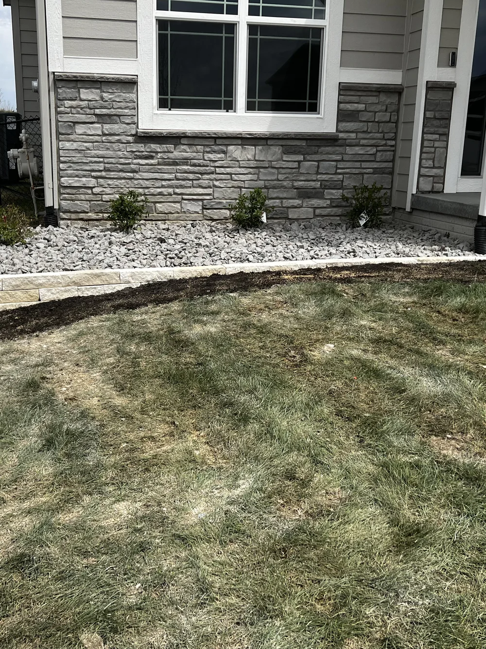 Foundation planting beds with limestone edging and rock mulch by Larkin Landscape and Design