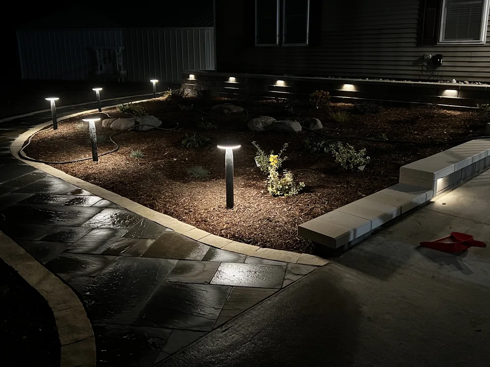 Landscape lighting highlighting a planting bed at dusk by Larkin Landscape and Design