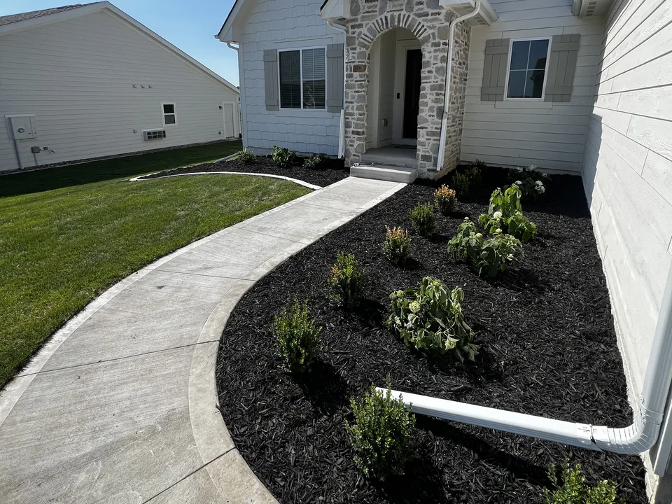 Layered planting bed with fresh mulch and clean edges by Larkin Landscape and Design
